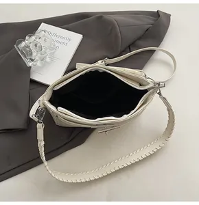 Detail view of cream leather handbag showing black fabric lining and woven strap edges