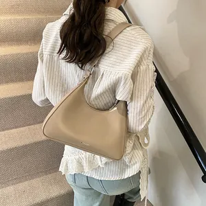 Close-up of minimalist beige PU leather hobo bag with wide shoulder strap