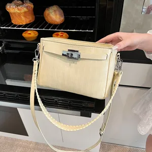 Detail of a creamy white leather bag with crocodile texture and silver twist lock closure
