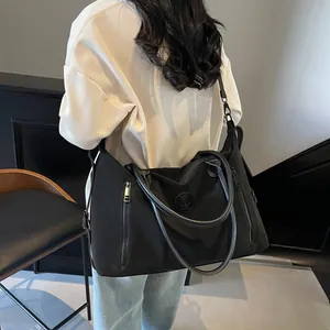 Model showing large black travel tote bag with metal zippers and shoulder strap back view