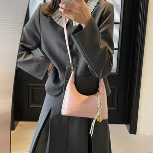 Detailed view of pink glossy PU leather hobo bag with unique charm and embossed texture