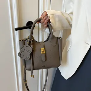 Détail du sac seau en cuir taupe avec ferrures dorées et breloque en forme de chien