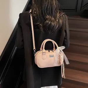 Detail of light pink leather bowling bag with lace bow and tassel on model's shoulder