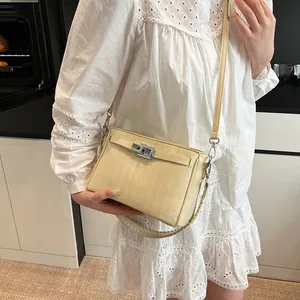 Close-up of minimalist beige crossbody bag with silver rotating lock and woven handle
