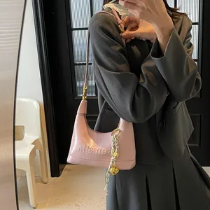 Mirror shot showing a pink patent leather hobo bag with embossed lettering and charm
