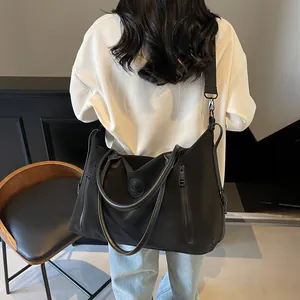 Rear view of model carrying a large black travel bag with adjustable strap and dual handles