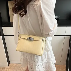 Detail of light beige Kelly style bag worn with a white lace dress for a commute look
