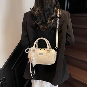 Close-up of beige crossbody bag with lace bow charm and shoulder strap on model