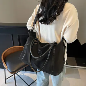 Rear view of model carrying large black travel tote with wide strap in modern room
