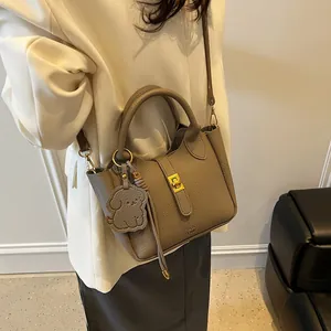 Détail du sac seau gris en cuir grainé avec breloque chien et fermoir doré rotatif