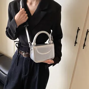 Mini sac à main carré argenté métallisé avec poignée épaisse porté par un mannequin