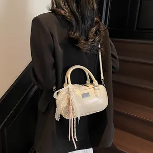 Close-up of beige bowling handbag with lace bow and charms on a wooden staircase