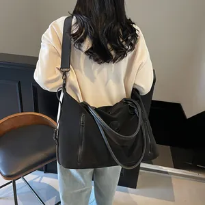 Detail of black large capacity travel tote with wide shoulder strap and circular logo