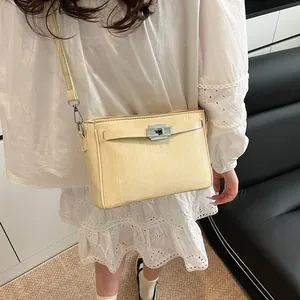 Detail of cream rectangular shoulder bag with silver turn-lock and vertical texture