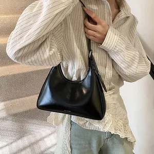 Detail view of glossy black crescent shoulder bag with silver buckle and NO FILTER text