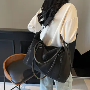 Close-up of black travel bag showing reinforced handles and detachable nylon shoulder strap