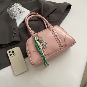 Detailed macro view of pink leather boston bag with silver bear charm and tassel ornament