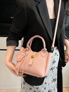 Sac seau en cuir rose avec pendentif chien et boucle dorée porté par un mannequin