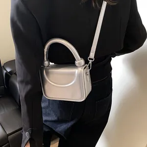 Gros plan d'un petit sac argenté métallisé avec finition miroir porté par un mannequin