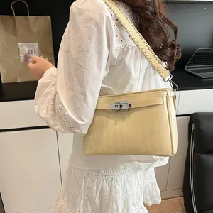 Detail of beige trapezoid shoulder bag with woven strap on model for daily styling