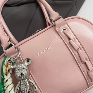 Close-up of pink leather Boston bag with silver logo and rhinestone bear charm