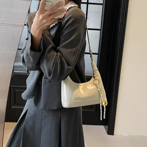 Close-up of white glossy hobo bag with embossed lettering and woven charm detail
