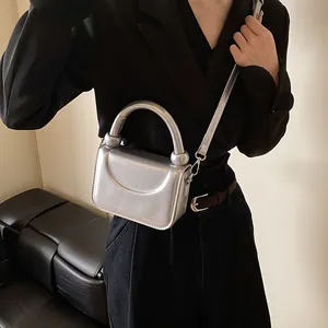 Vue détaillée du mini sac bandoulière argenté avec finition métallique et poignée sur modèle