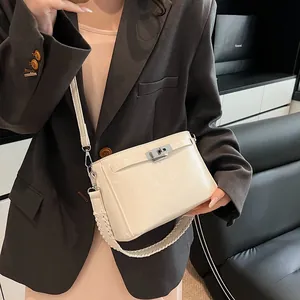 Detail of cream white handbag with silver twist lock and braided handle on model