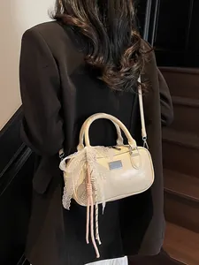 Cream vintage Boston bag with bow charm shown on a shoulder in a stylish indoor setting
