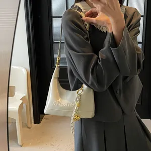 Close-up of cream faux leather hobo bag with embossed lettering and golden charm details