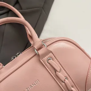 Close-up of pink ZIANDI shoulder bag featuring embossed logo and braided strap detail