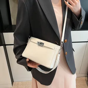 Detail of cream Kelly-style bag featuring silver turn-lock closure and woven handle