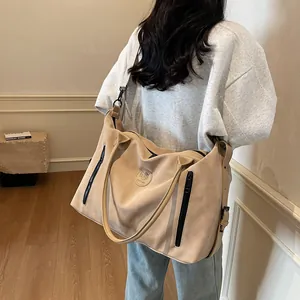 Detailed macro view of beige travel bag with side zipper pockets and embossed round logo