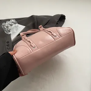 Detailed view of pink patent leather Boston bag featuring woven trim and metallic rings