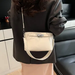 Detail of off-white Kelly bag with silver twist lock and woven handle on a model