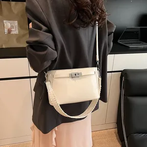 Detail of cream white handbag featuring silver twist lock and woven shoulder strap