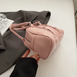 Close-up of pink glossy patent leather Boston bag with silver zipper detail and top handles