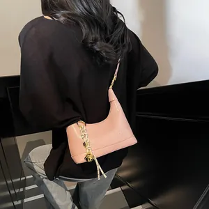 Detail of pink faux leather half-moon bag featuring embossed logo and gold hardware