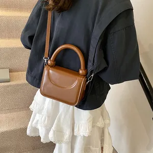 Petit sac carré marron en cuir avec poignée ronde épaisse et couture décorative