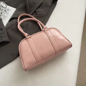 Detail of light pink Boston handbag with glossy finish and secure double handles