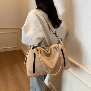 Detailed view of beige large travel bag with adjustable strap worn by a model