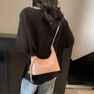 Detailed side view of pink glossy hobo bag with embossed lettering and shoulder strap