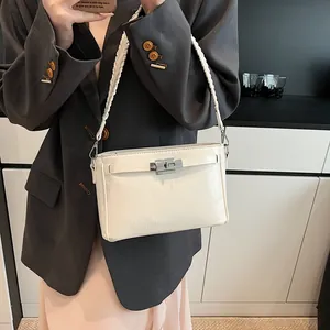 Detailed view of white Kelly bag featuring a silver metal turn-lock and woven strap