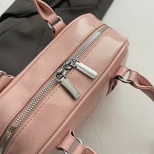 Detail of pink faux leather bag showing silver double zippers and embossed texture