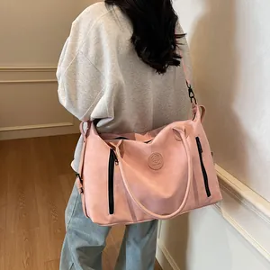 Pink travel bag detail featuring the logo, side zippers and detachable shoulder strap