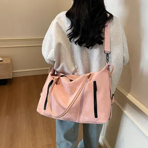Pink large travel tote with dual front zippers and crossbody strap shown on model