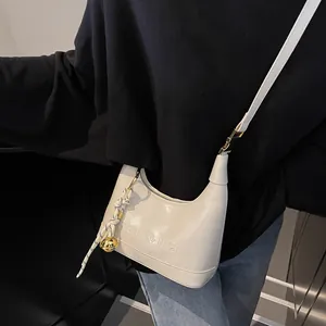 Detail of white PU leather hobo bag featuring sen&jia lettering and a gold bell charm