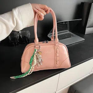 Detail of pink glossy Boston bag with diamond bear charm and woven rope accent