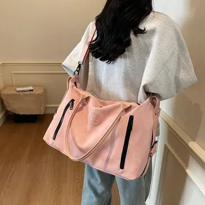 Rear view of model carrying pink large travel bag with dual black zippers and wide strap