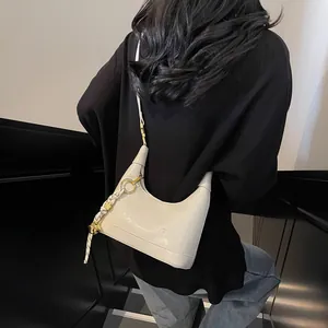 Detail of cream hobo bag with embossed lettering and black braided cord charm